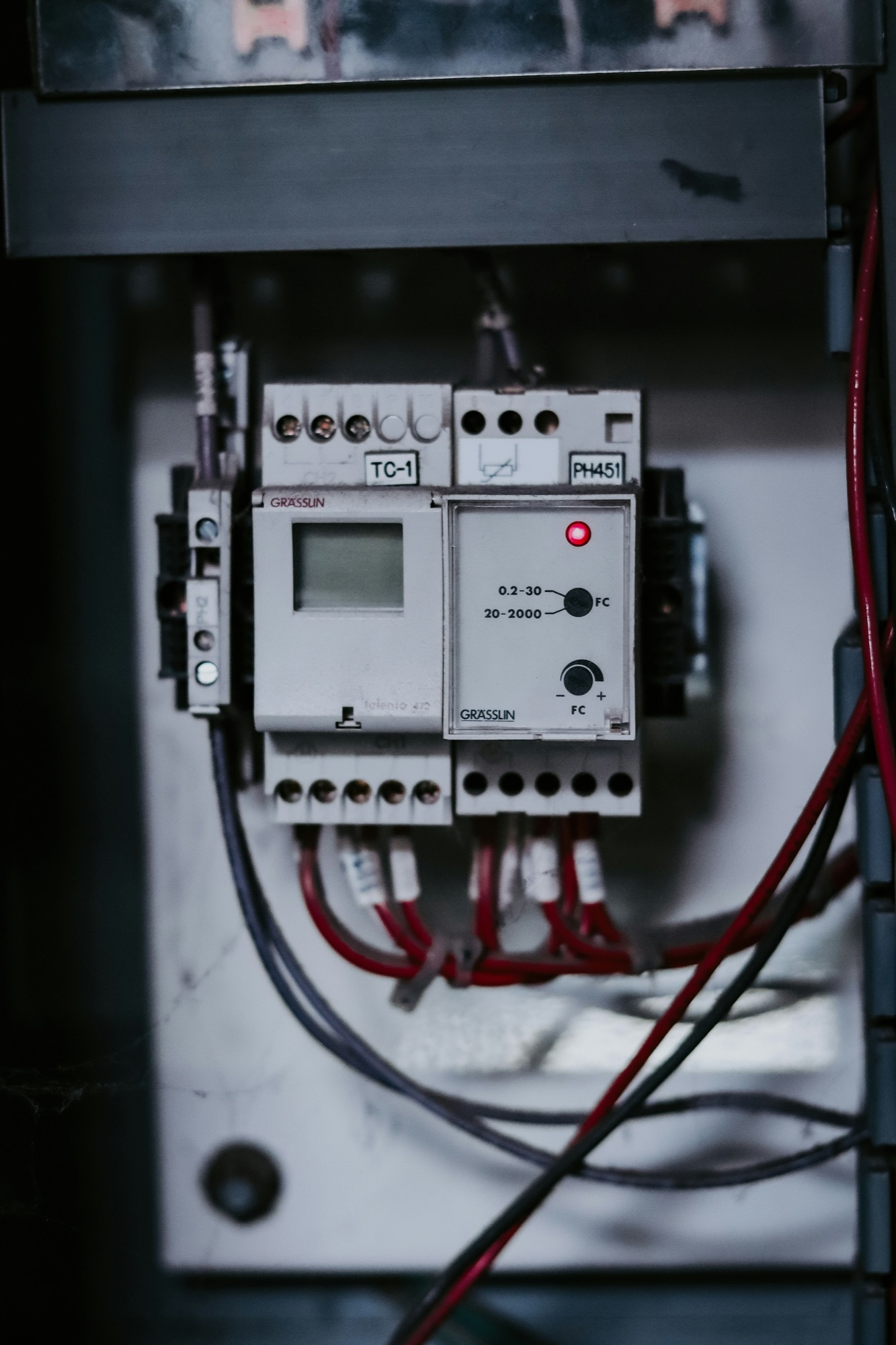 A controller module and red wiring inside a dark enclosure.