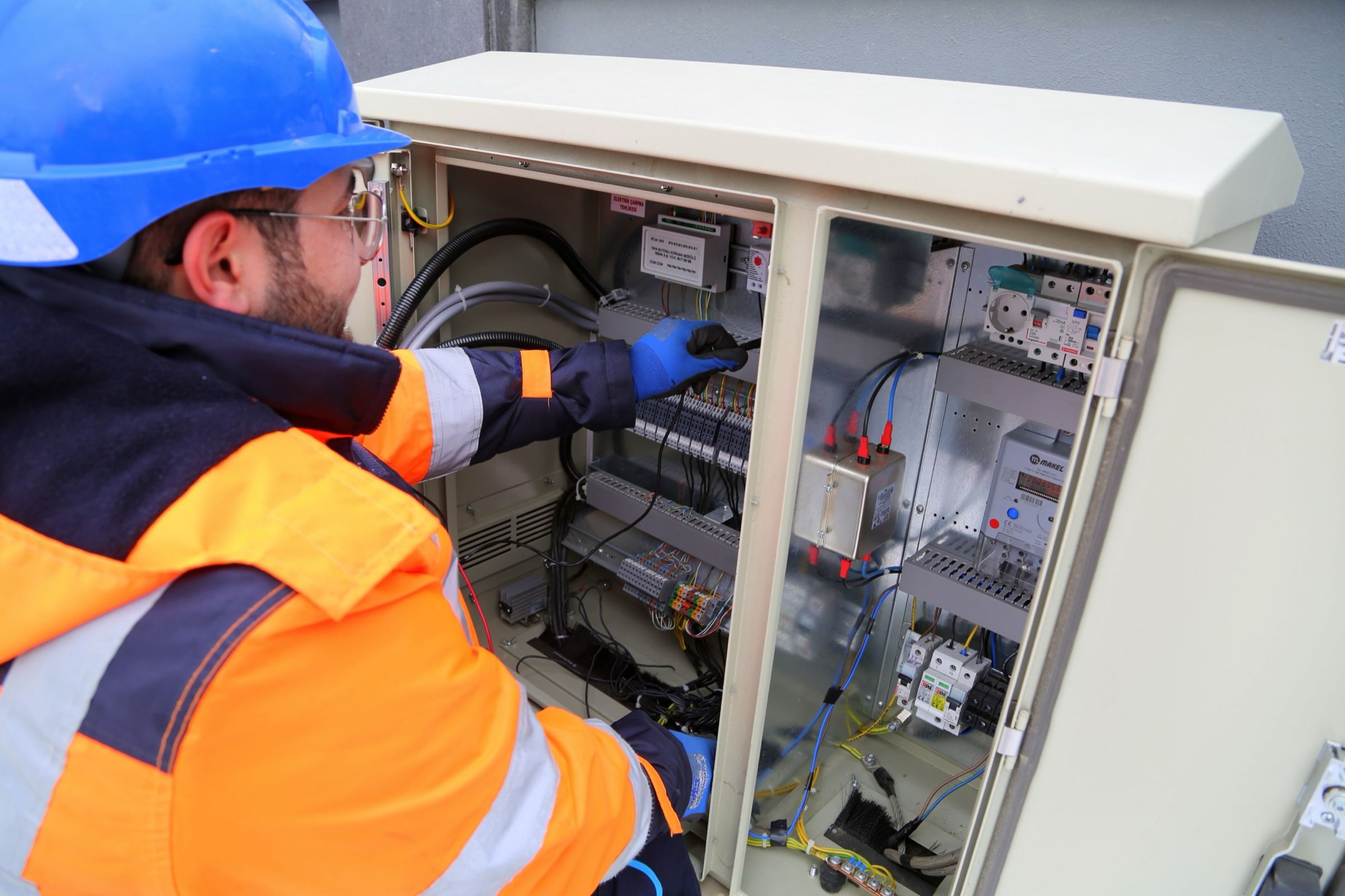 A technician wiring an outdoor equipment cabinet on site. Illustrative photograph.