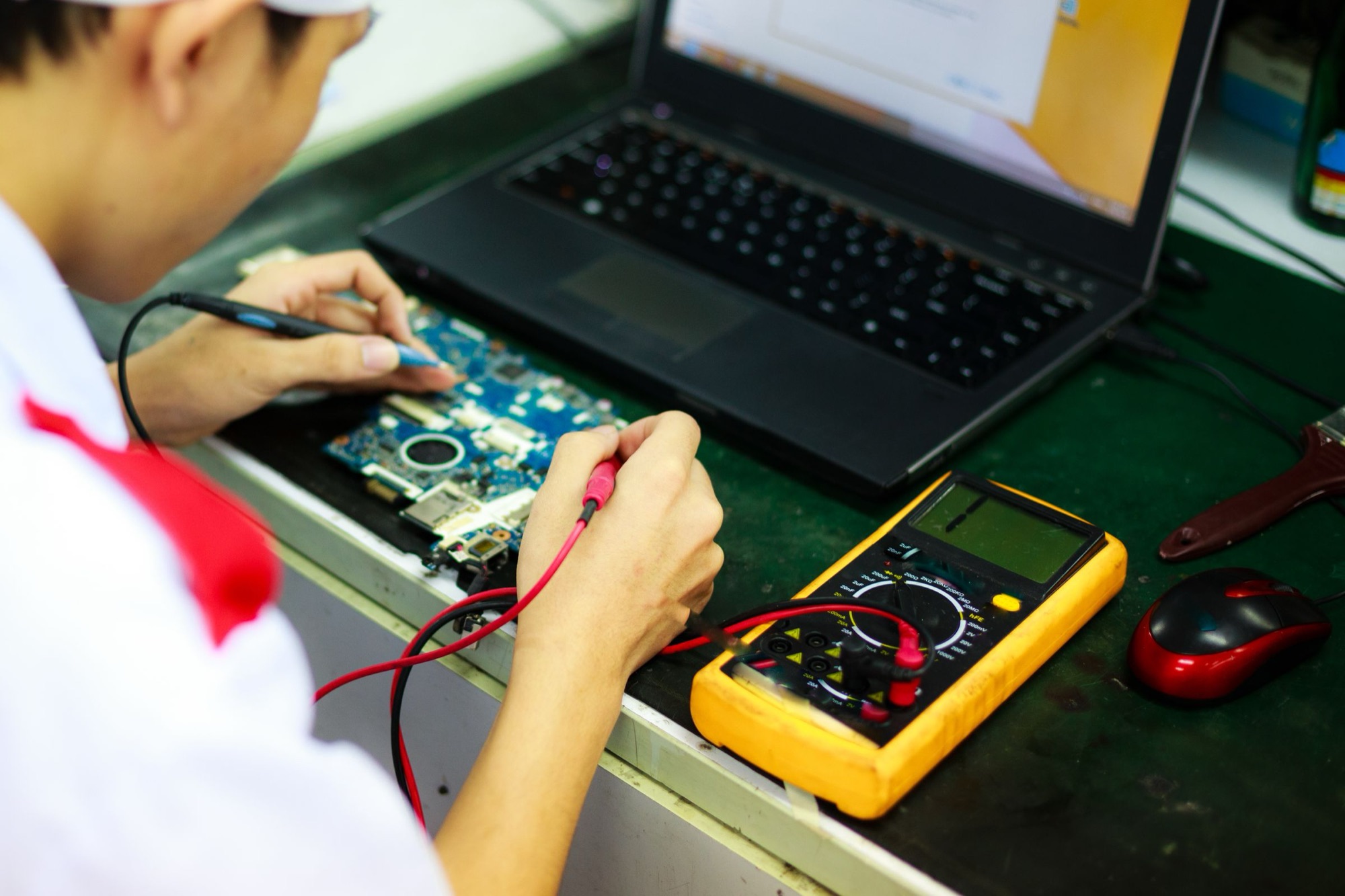 A technician probing a circuit board with a multimeter.
