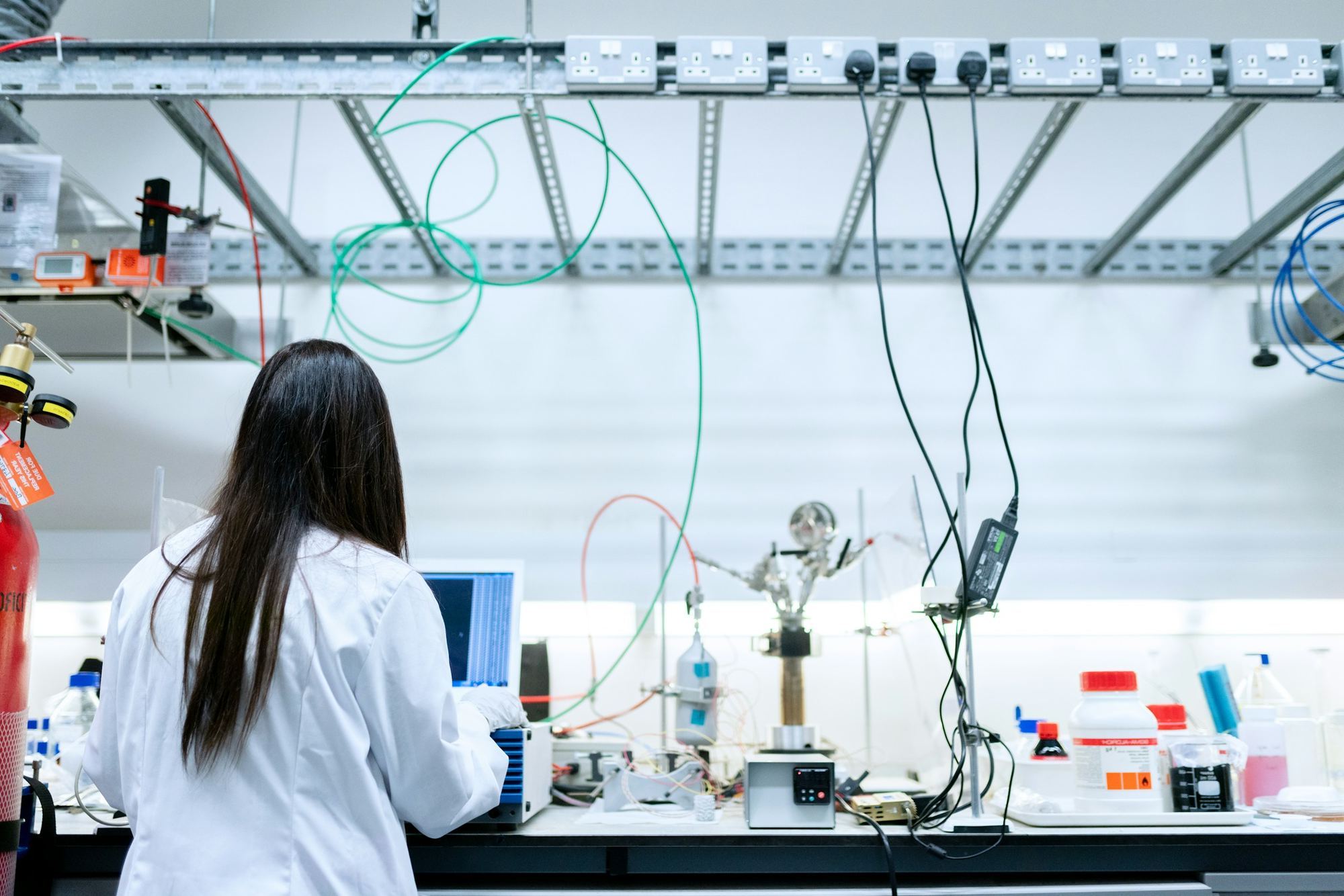 A researcher at a laboratory bench with instruments and a laptop. Illustrative photograph.