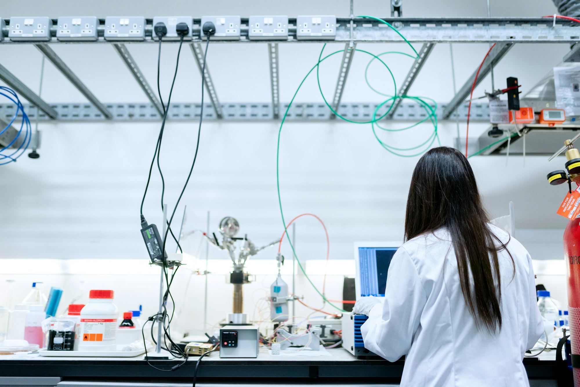 A researcher at a laboratory bench with instruments and a laptop. Illustrative photograph.